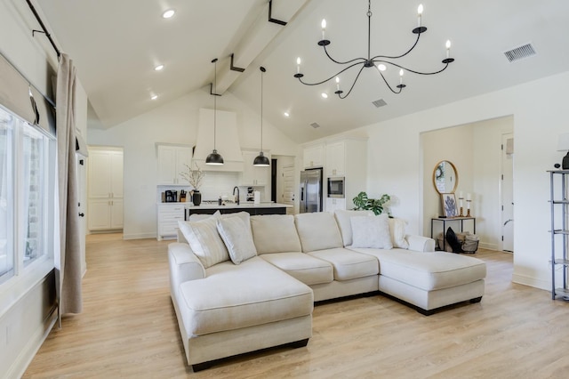 living room with an inviting chandelier, beam ceiling, light wood-type flooring, and a wealth of natural light