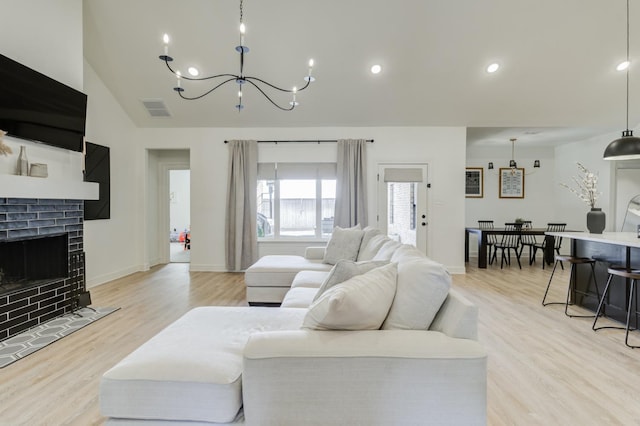 living room with a brick fireplace, a chandelier, and light hardwood / wood-style floors