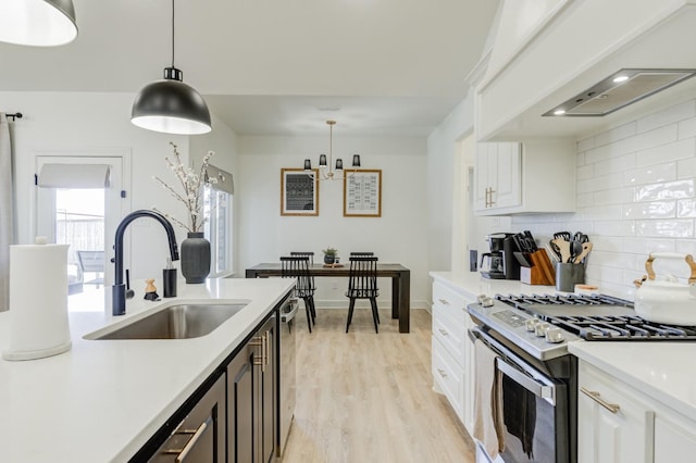 kitchen featuring sink, white cabinetry, decorative light fixtures, appliances with stainless steel finishes, and custom range hood