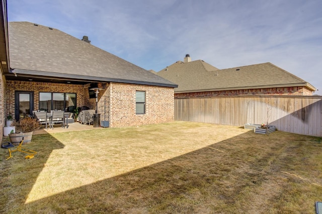 back of house with a patio and a lawn