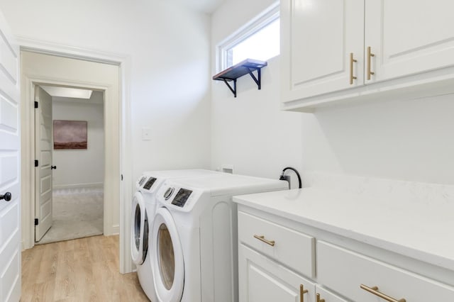 laundry room with cabinets, washer and clothes dryer, and light hardwood / wood-style floors