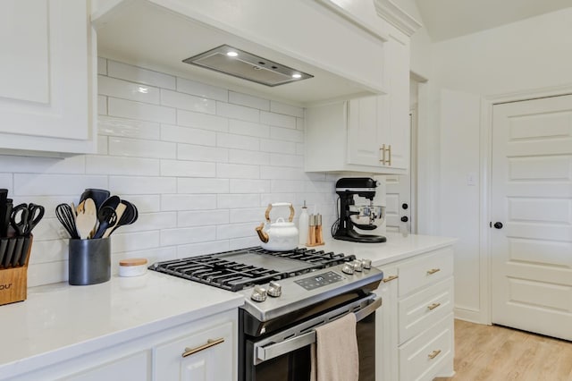 kitchen with backsplash, light hardwood / wood-style flooring, stainless steel range with gas stovetop, and white cabinets