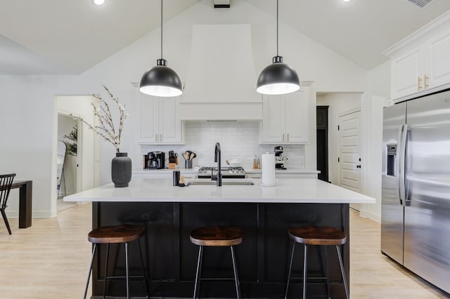 kitchen with white cabinets, pendant lighting, stainless steel fridge, and a kitchen breakfast bar