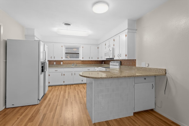 4416 33rd St, Lubbock, TX 79410 - kitchen with white appliances, a peninsula, light wood finished floors, white cabinets, and decorative backsplash