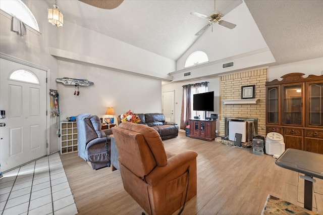 living room with a textured ceiling, high vaulted ceiling, ceiling fan, and light wood-type flooring