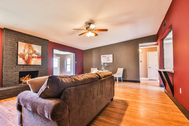 living room featuring a brick fireplace, ceiling fan, and light hardwood / wood-style flooring