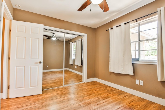 unfurnished bedroom with multiple windows, ceiling fan, light wood-type flooring, and a closet