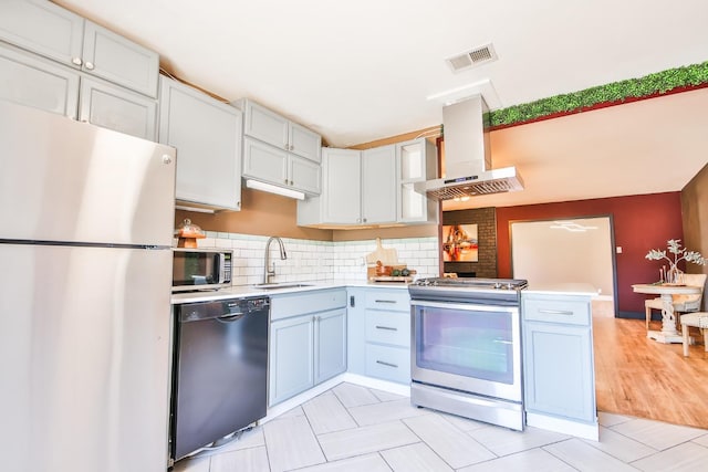 kitchen featuring sink, appliances with stainless steel finishes, white cabinetry, tasteful backsplash, and island range hood