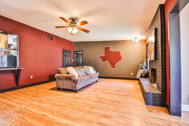 living room with ceiling fan, light hardwood / wood-style floors, and a brick fireplace