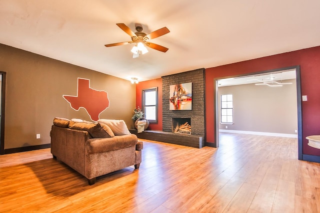 living room featuring a brick fireplace, vaulted ceiling, light hardwood / wood-style floors, and ceiling fan