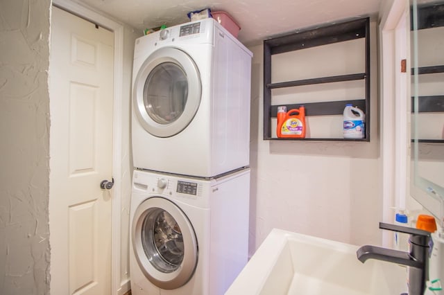 washroom with stacked washer and clothes dryer and sink