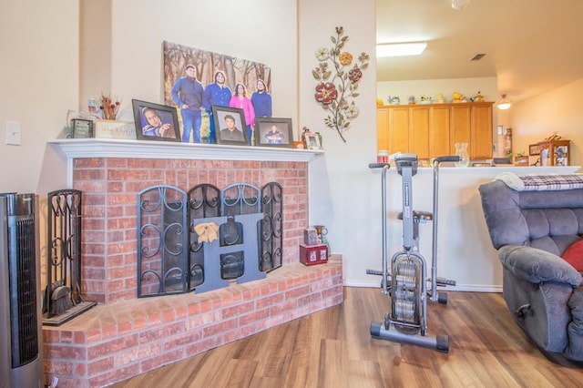 living room with wood-type flooring and a brick fireplace