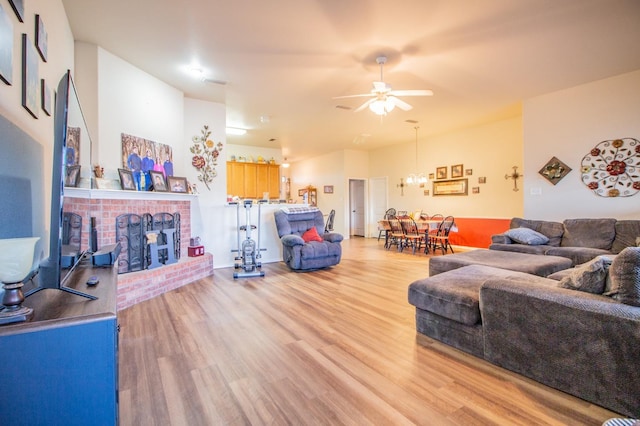 living room with a brick fireplace, ceiling fan, and light hardwood / wood-style flooring