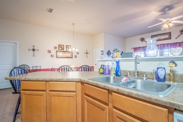 kitchen with sink, light tile patterned floors, a breakfast bar area, ceiling fan, and decorative light fixtures