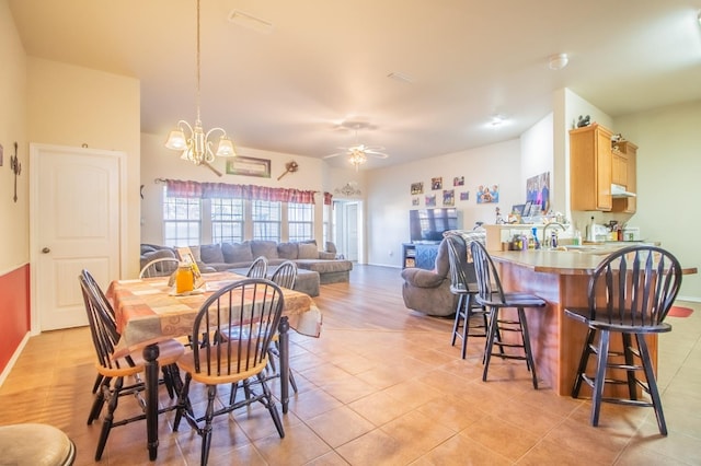 tiled dining area featuring sink and ceiling fan with notable chandelier