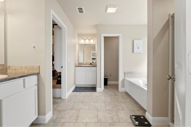 bathroom featuring vanity, a bath, and tile patterned floors