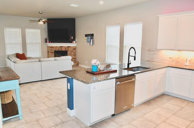 kitchen featuring sink, dark stone countertops, dishwasher, kitchen peninsula, and white cabinets