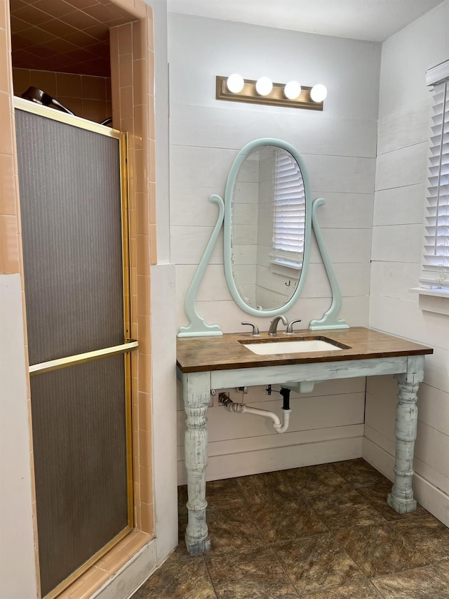 bathroom featuring an enclosed shower, sink, and tile walls