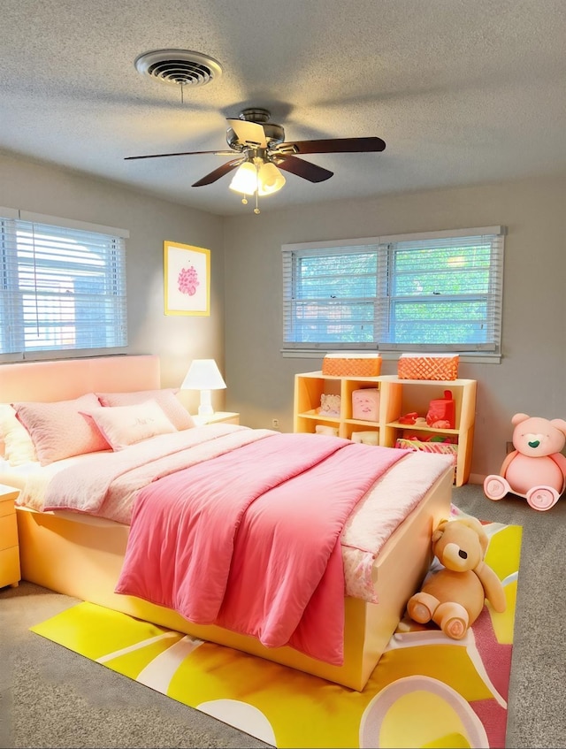 carpeted bedroom with ceiling fan and a textured ceiling