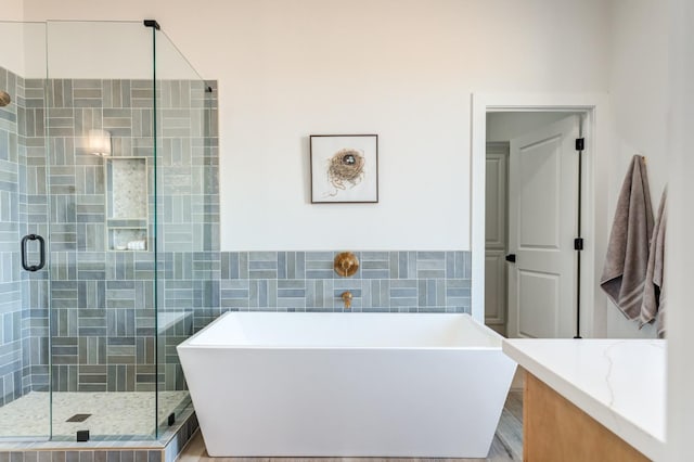 bathroom with vanity, independent shower and bath, and tile walls