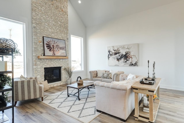 living room featuring a fireplace, high vaulted ceiling, and light hardwood / wood-style flooring