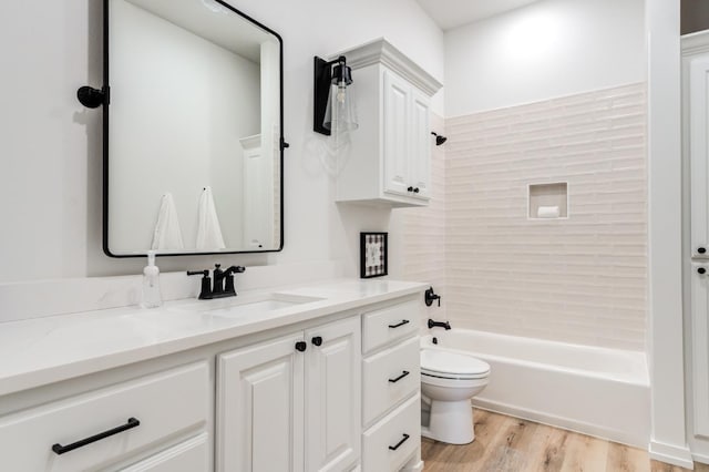 full bathroom with hardwood / wood-style flooring, tiled shower / bath, vanity, and toilet