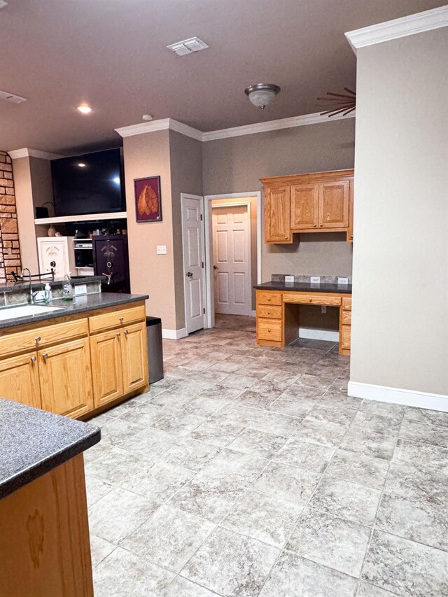 kitchen with sink, crown molding, and built in desk