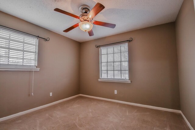 unfurnished room featuring a wealth of natural light, carpet floors, a textured ceiling, and ceiling fan