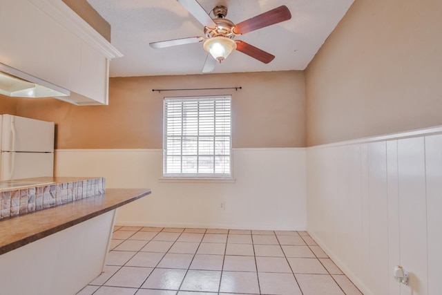 kitchen with white refrigerator, white cabinetry, ceiling fan, and light tile patterned floors