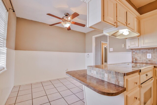 kitchen with decorative backsplash, black electric stovetop, light tile patterned floors, ceiling fan, and white oven