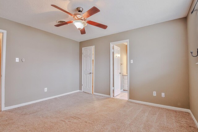 unfurnished bedroom with light carpet, ensuite bath, a textured ceiling, and ceiling fan