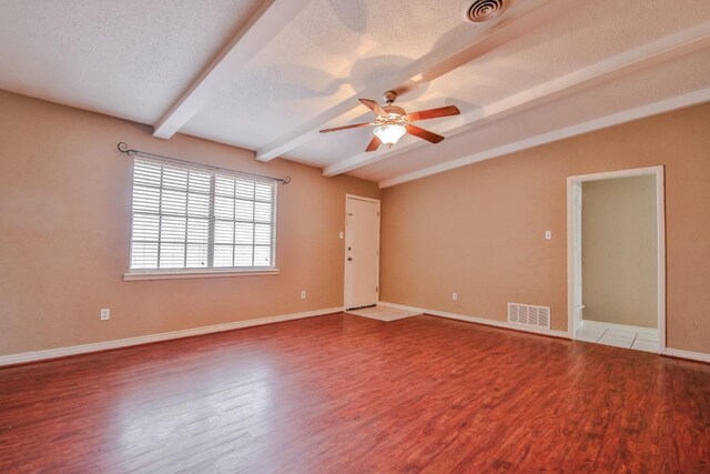 unfurnished room featuring lofted ceiling with beams, ceiling fan, hardwood / wood-style floors, and a textured ceiling