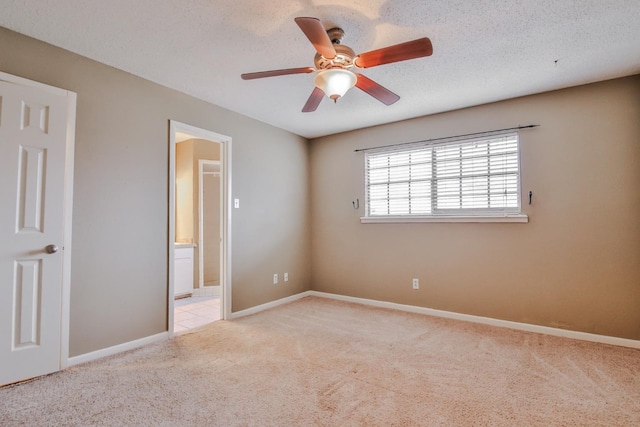 unfurnished room featuring ceiling fan, light colored carpet, and a textured ceiling