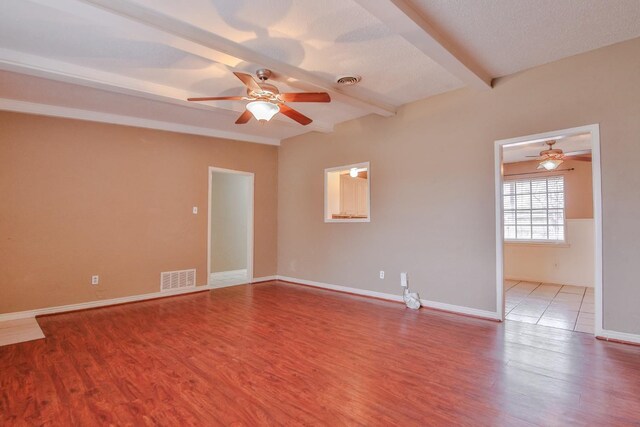 unfurnished room with beam ceiling, light hardwood / wood-style floors, ceiling fan, and a textured ceiling