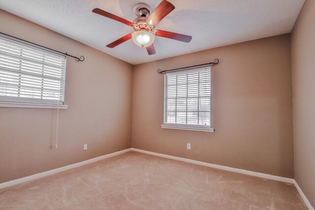 unfurnished room with plenty of natural light, light colored carpet, a textured ceiling, and ceiling fan