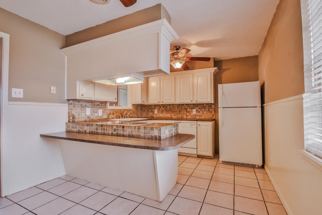 kitchen featuring tasteful backsplash, light tile patterned floors, ceiling fan, kitchen peninsula, and white appliances