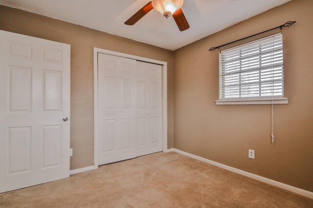 unfurnished bedroom featuring light carpet, a closet, and ceiling fan