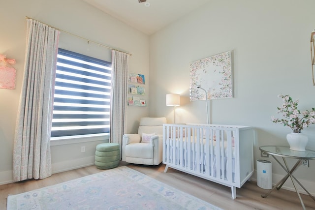 bedroom with a crib and light hardwood / wood-style floors