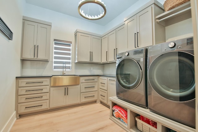 laundry room with sink, cabinets, washing machine and clothes dryer, and light wood-type flooring