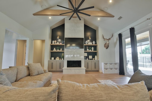 living room with high vaulted ceiling, light hardwood / wood-style floors, a tile fireplace, and beamed ceiling