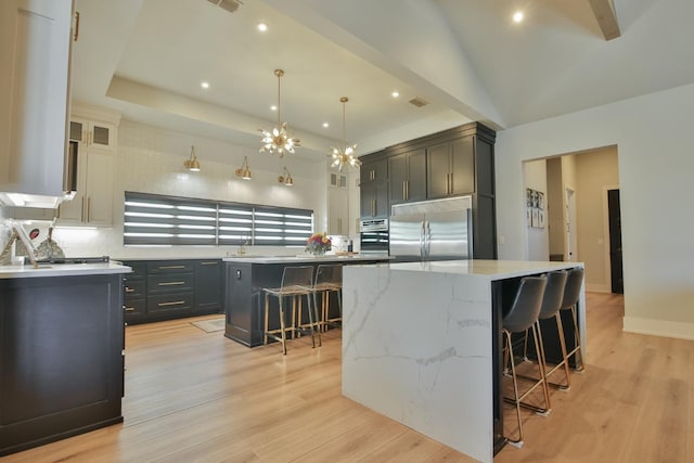 kitchen featuring appliances with stainless steel finishes, a spacious island, a breakfast bar area, backsplash, and light hardwood / wood-style flooring