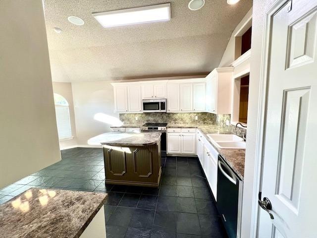 kitchen featuring sink, appliances with stainless steel finishes, white cabinetry, a center island, and decorative backsplash