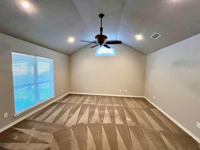 spare room with lofted ceiling, a textured ceiling, carpet, and ceiling fan