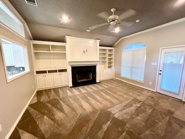 unfurnished living room featuring vaulted ceiling, carpet flooring, ceiling fan, crown molding, and a textured ceiling