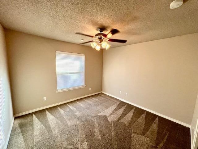 unfurnished room with ceiling fan, carpet, and a textured ceiling