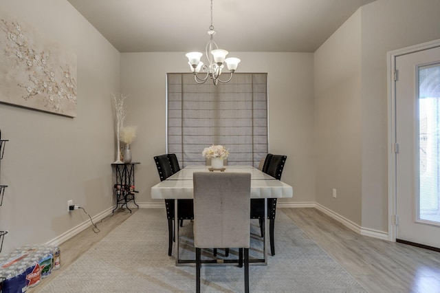 dining area with plenty of natural light, an inviting chandelier, and light hardwood / wood-style flooring