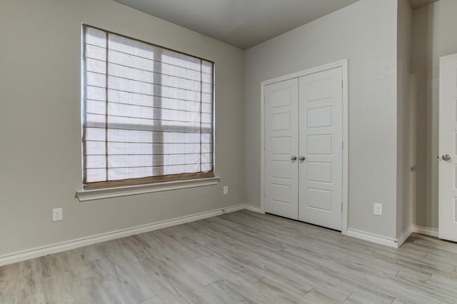 unfurnished bedroom with light hardwood / wood-style flooring and a closet