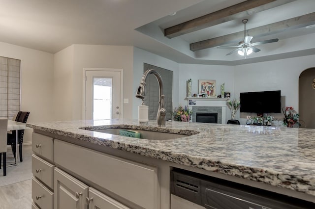 kitchen featuring sink, stainless steel dishwasher, ceiling fan, light stone countertops, and light wood-type flooring