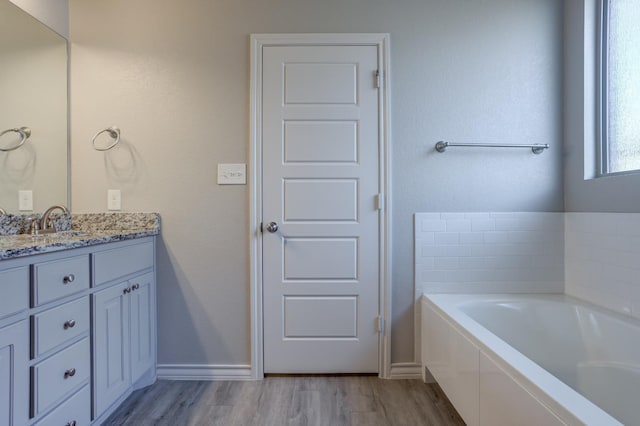 bathroom with vanity, wood-type flooring, and tiled tub