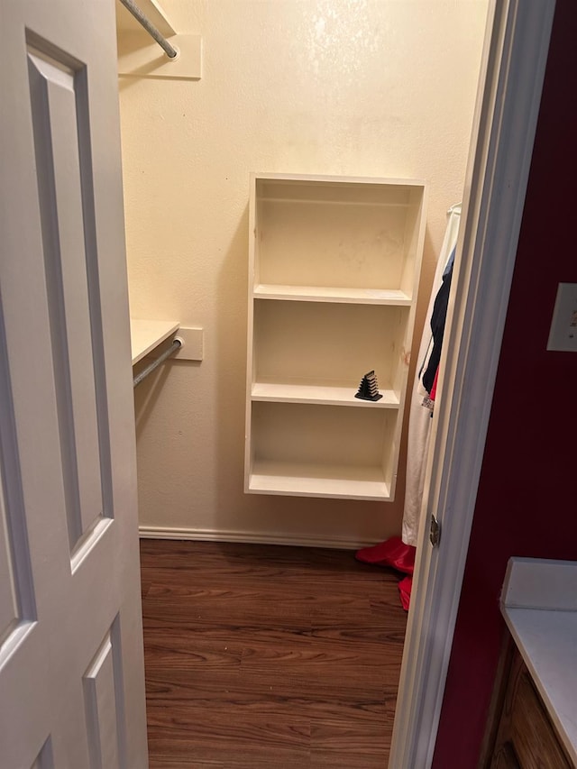 walk in closet with dark wood-type flooring